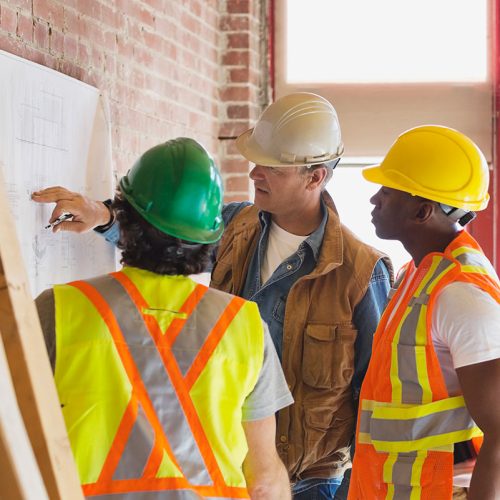 Foreman explaining blueprint to tradesmen at construction site